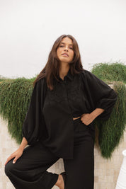 A model wearing the Rosalind Shirt in colour Black (Black), from the front, showing the whole outfit