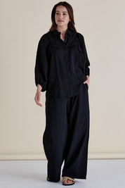A model wearing the Rosalind Shirt in colour Black (Black), from the front, showing the whole outfit