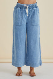 A model wearing the Saffra Relax Leg Jean in colour Midwash (Blue), from the front, cropped image