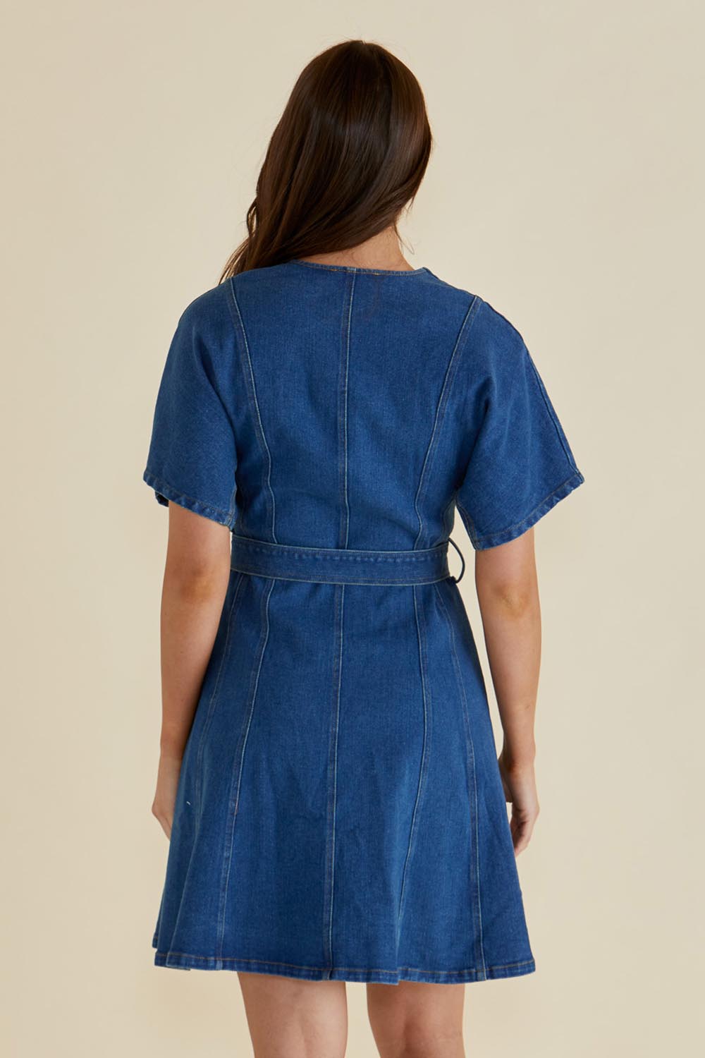 A model wearing the Fiori Denim Dress in colour Midwash (Blue), from the back