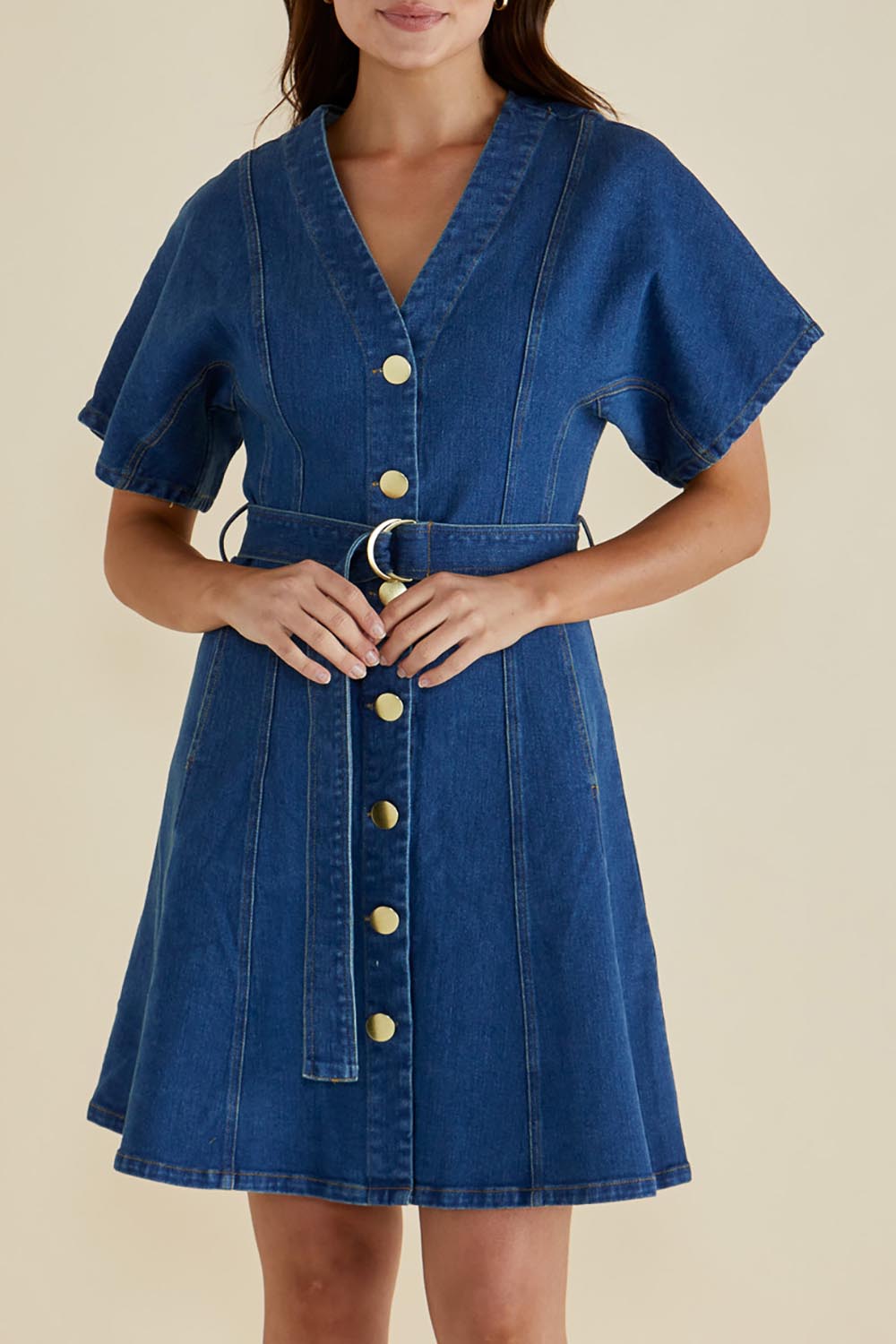A model wearing the Fiori Denim Dress in colour Midwash (Blue), from the front, cropped image