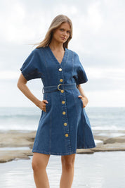 A model wearing the Fiori Denim Dress in colour Midwash (Blue), from the front, showing the whole outfit