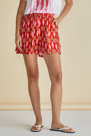A model wearing the Copacabana Short in colour Sardinia (Red), from the front, cropped image