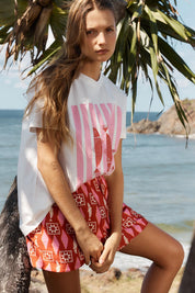 A model wearing the Copacabana Short in colour Sardinia (Red), from the front, showing the whole outfit