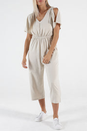 A model wearing the Jules Linen Jumpsuit in colour Wheat, from the front, cropped image