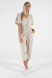 A model wearing the Jules Linen Jumpsuit in colour Wheat, from the front, showing the whole outfit