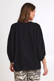 Model Madelinec wearing size 10 of the Bella Blouse – Black in colour Black, from the back