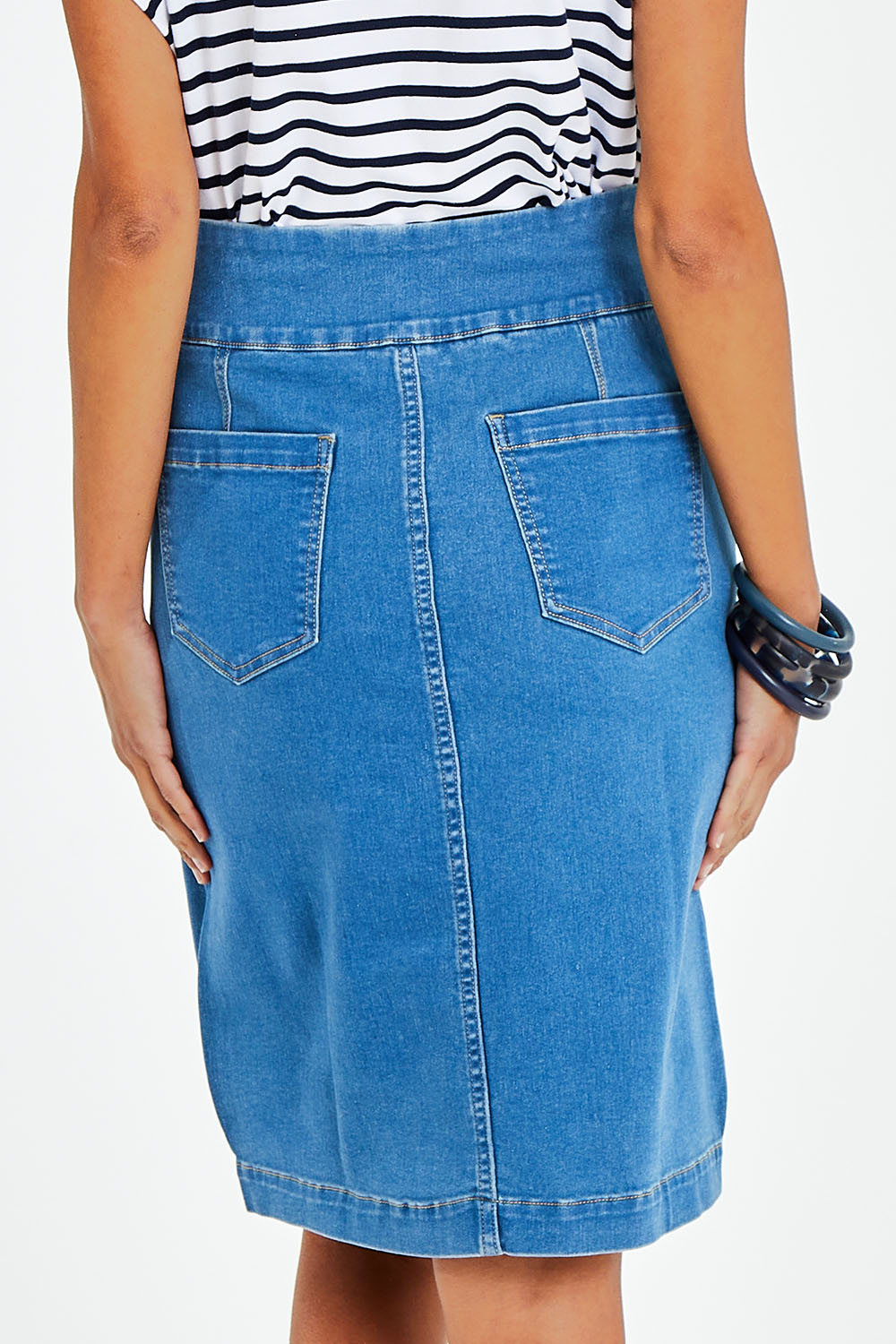 Model Vitoria wearing size 10 of The Pull On Denim Skirt in colour Middenim (Blue), from the back