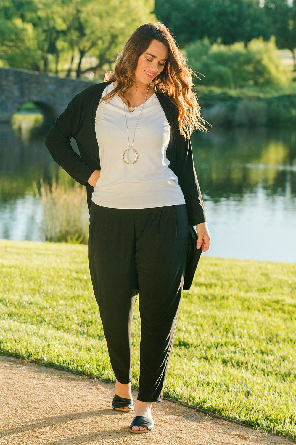 Model Laura wearing size 14 of The Recycled Flat Front Pull On Pant in colour Black (Black), from the front, showing the whole outfit
