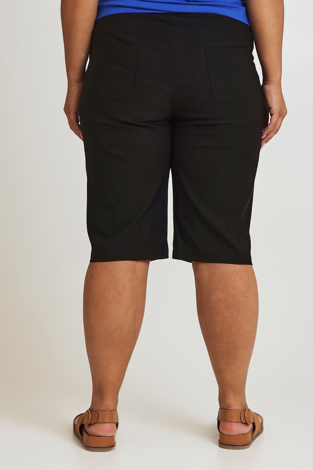 Model Ashleigh wearing size 16 of The Cargo Short in colour Black (Black), from the back
