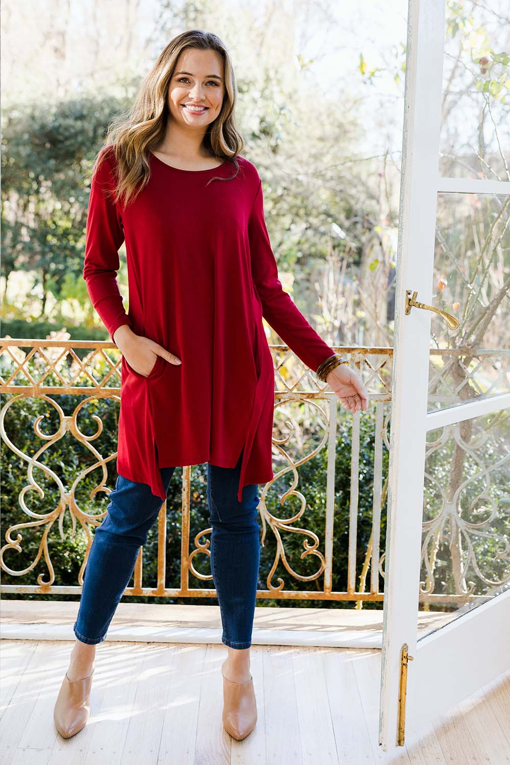 Model Tahlia wearing size 10 of The Crew Neck High Low Tunic in colour Redberry (Red), from the front, showing the whole outfit