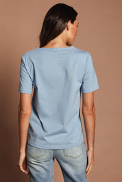 Model Madeline wearing size 10 of The Keepers Tee in colour Dustyblue (Blue), from the back