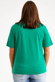 Model Monique wearing size 14 of The Keepers Tee in colour Emerald (Green), from the back