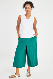 Model Noli wearing size 14 of The Recycled Pleated Culottes in colour Emerald (Green), from the front, showing the whole outfit