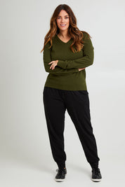 Model Laura wearing size L of The Keepers Soft V Neck Jumper in colour Darkolive (Green), from the front, showing the whole outfit
