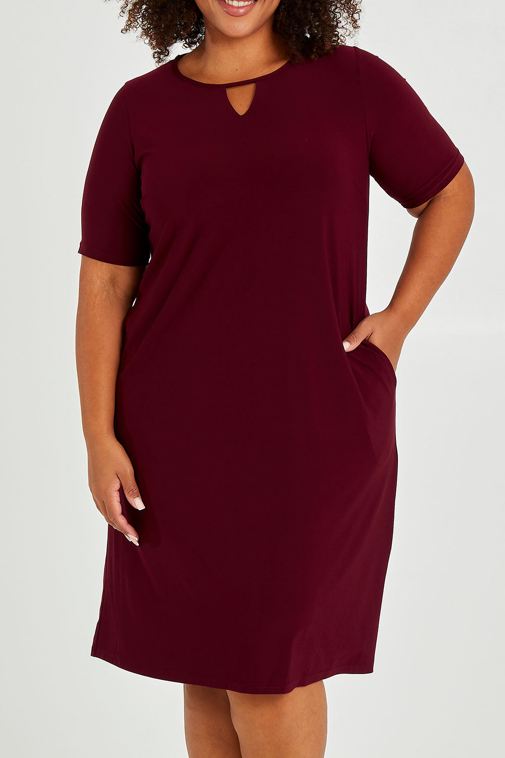 Model Alexis wearing size 16 of The Recycled Easy Wear Keyhole Dress in colour Burgundy (Purple), from the front, cropped image