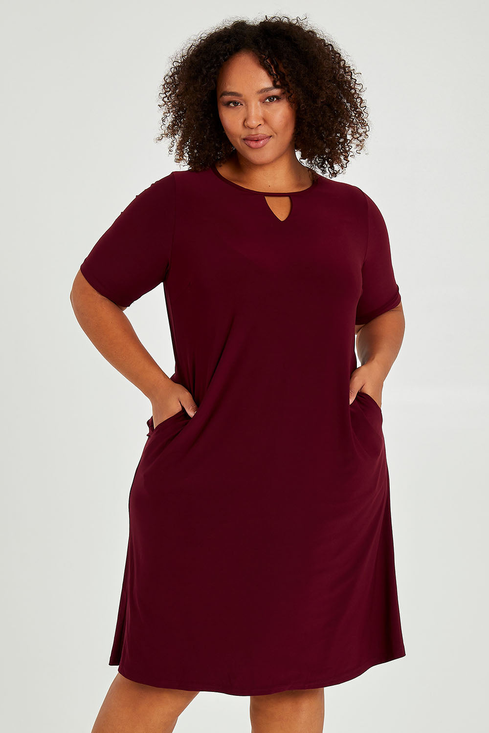 Model Alexis wearing size 16 of The Recycled Easy Wear Keyhole Dress in colour Burgundy (Purple), from the front, cropped image