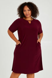 Model Alexis wearing size 16 of The Recycled Easy Wear Keyhole Dress in colour Burgundy (Purple), from the front, cropped image