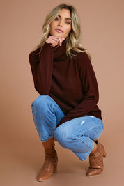 Model Alice wearing size S of The Keepers Soft Roll Neck Jumper in colour Burntplum (Purple), from the front, showing the whole outfit
