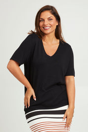 Model Monique wearing size L of The Transeasonal Short Sleeve Jumper in colour Black (Black), from the front, cropped image