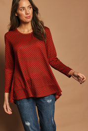 Model Madeline wearing size 10 of The Spot Swing Knit Tee in colour Burntred (Red), from the front, cropped image