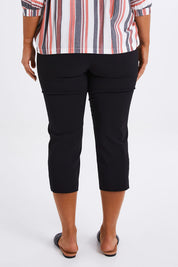 Model Monique wearing size 14 of The X Detail Capri Pant in colour Black (Black), from the back