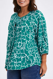 Model Monique wearing size 14 of The Keepers Crew Neck Printed Shirt in colour Tealwhite (Green), from the front, cropped image