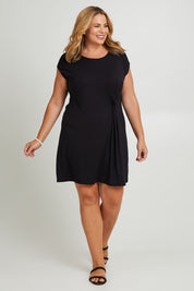 Model Fiona wearing size 16 of The Luxe Twist Detail Tee Dress in colour Black (Black), from the front, showing the whole outfit