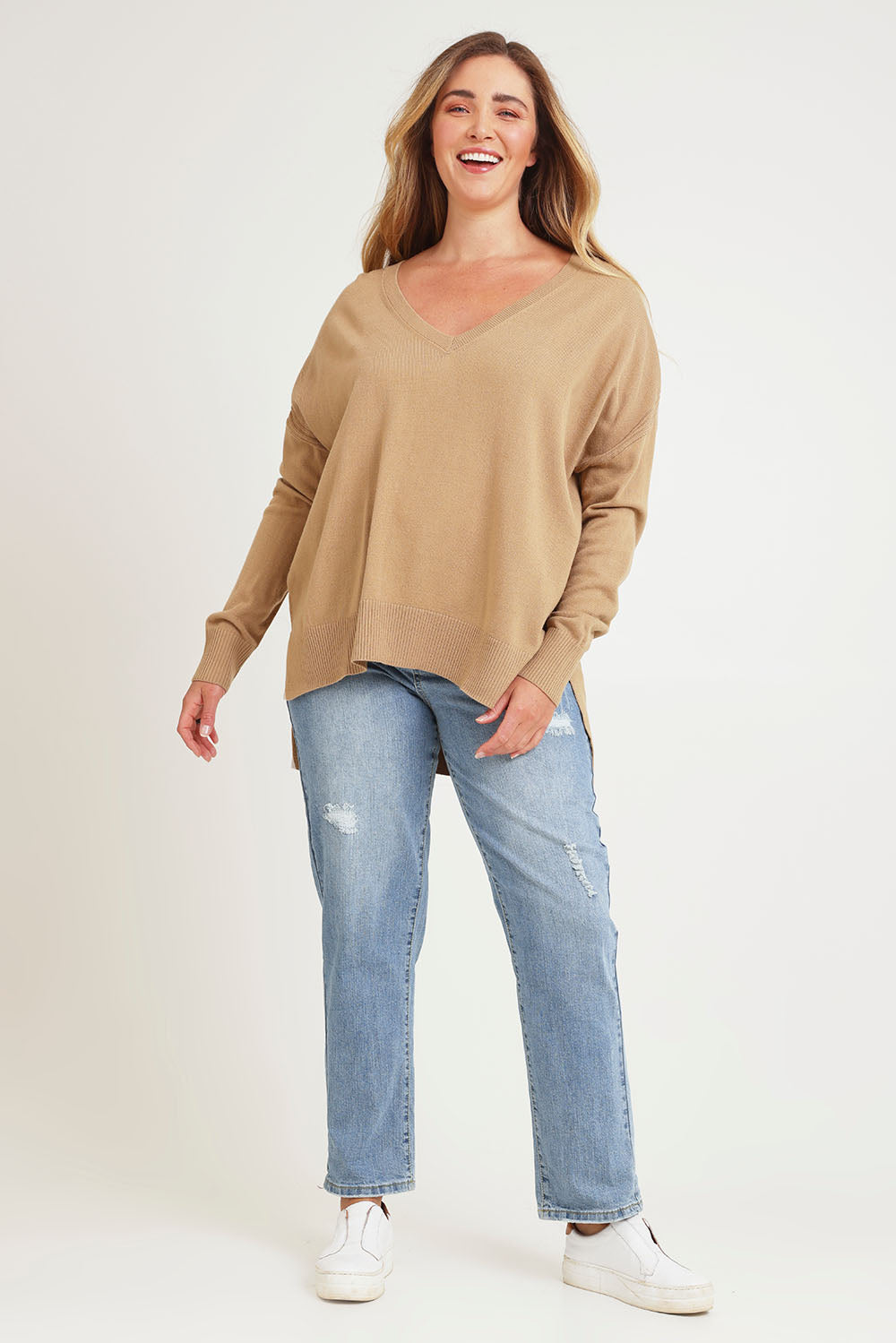 Model Chanel wearing size XL of The High Low V Neck Jumper in colour Fawn, from the front, showing the whole outfit