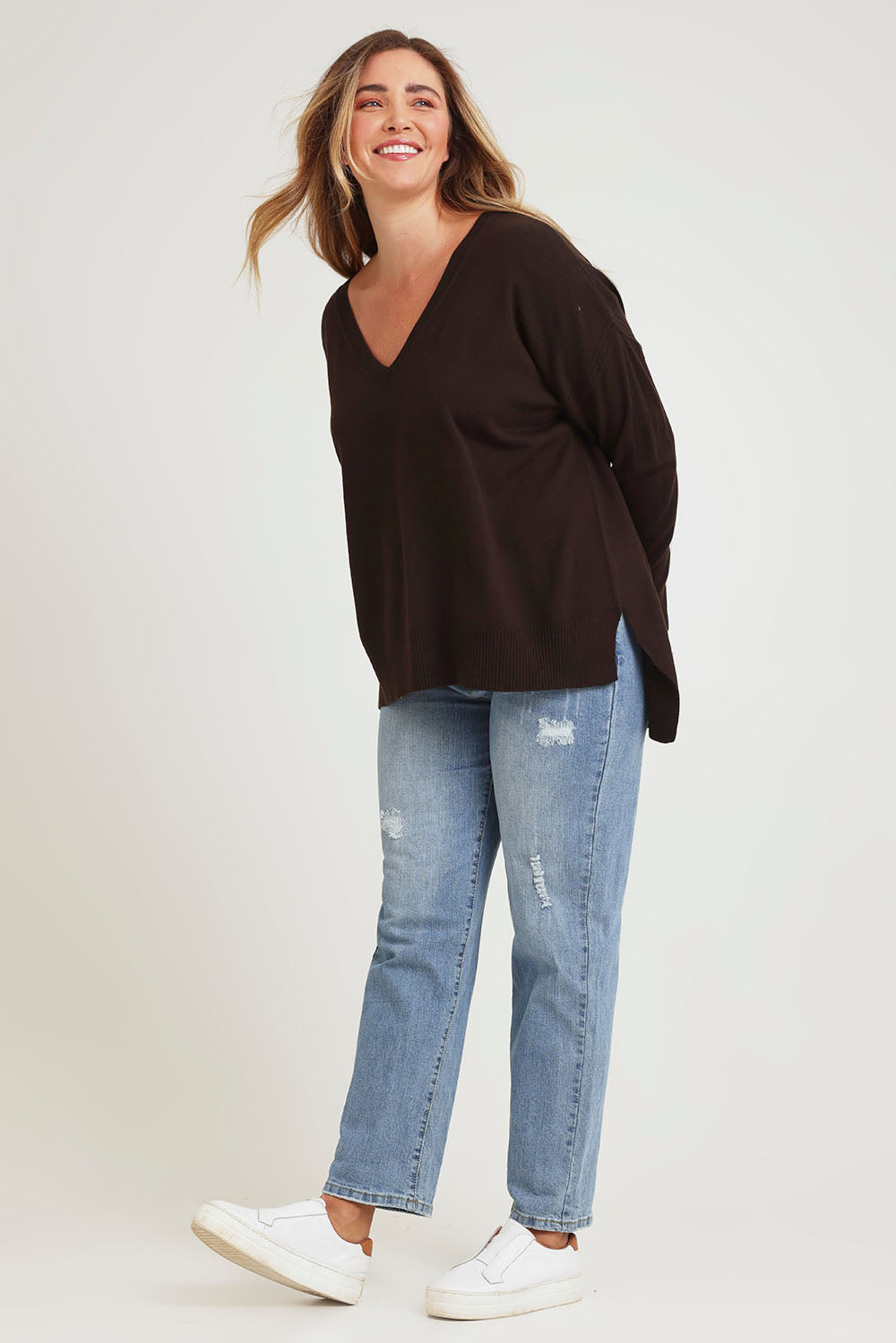 Model Chanel wearing size XL of The High Low V Neck Jumper in colour Sable, from the front, showing the whole outfit