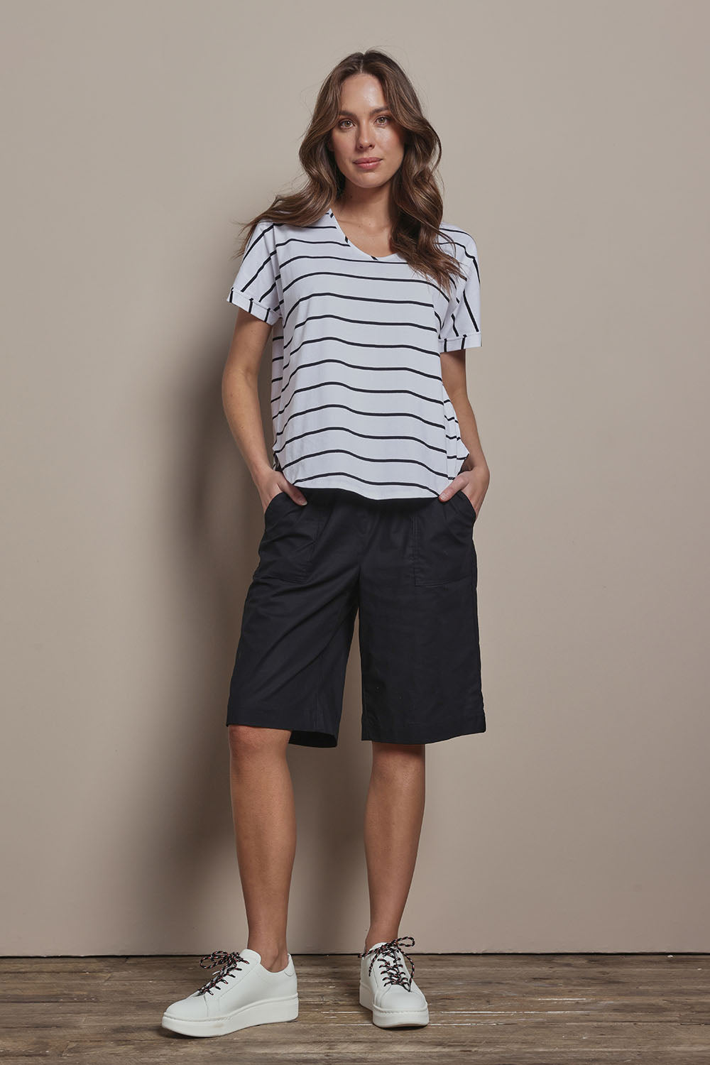 Model Madeline wearing size 10 of The Striped V Neck Tee in colour Whiteblack (White), from the front, showing the whole outfit