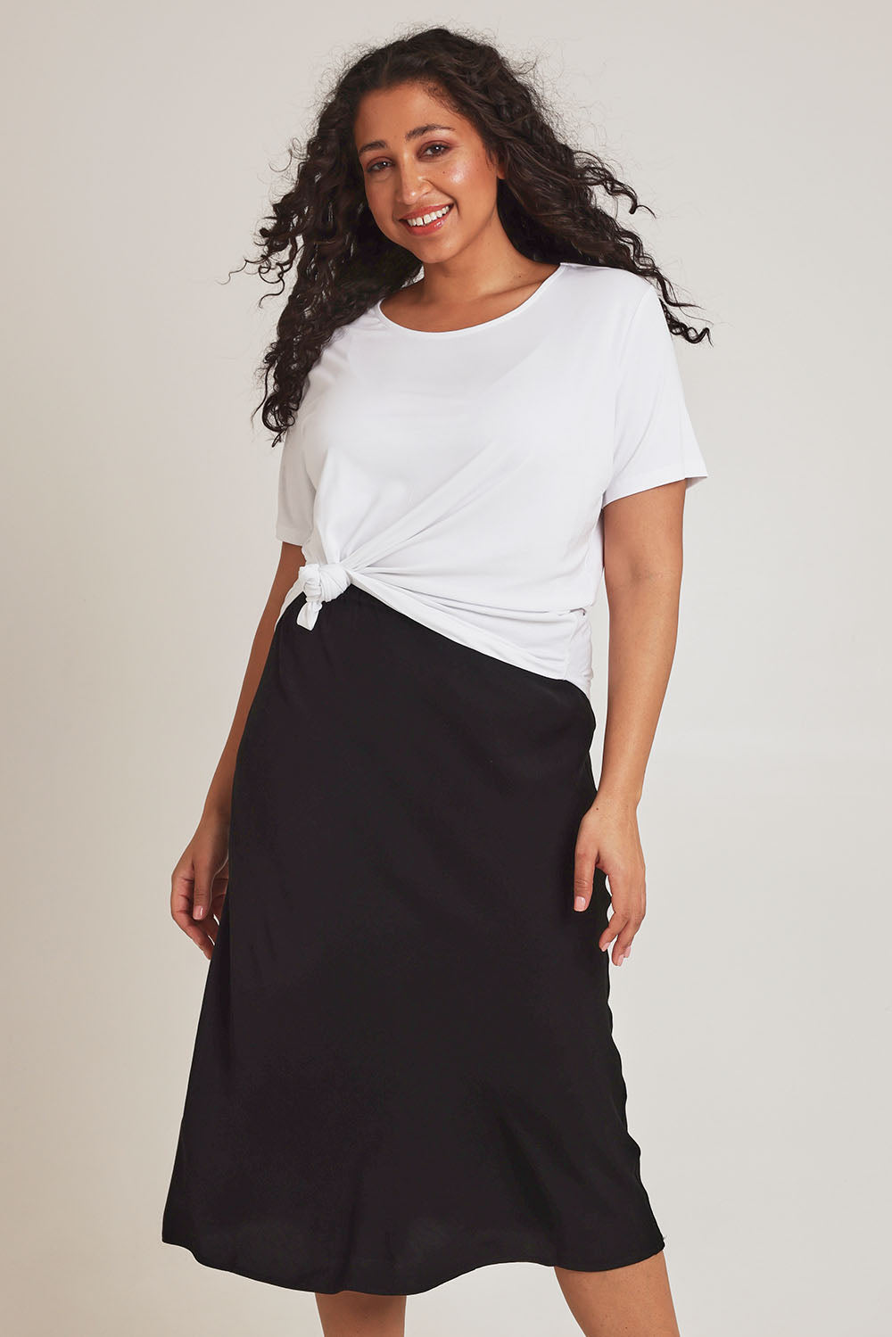 Model Terri-Leigh wearing size 14 of The Pull On Bias Skirt in colour Black (Black), from the front, cropped image