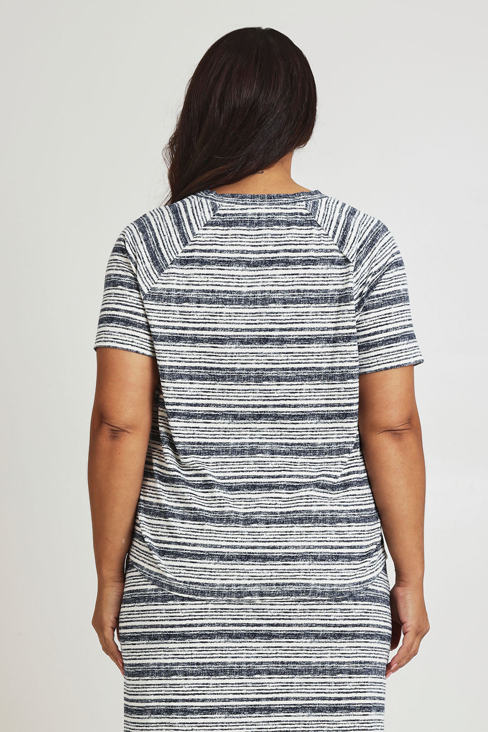Model Ashleigh wearing size 16 of The Striped Raglan Sleeve Tee in colour Navystripe (Blue), from the back