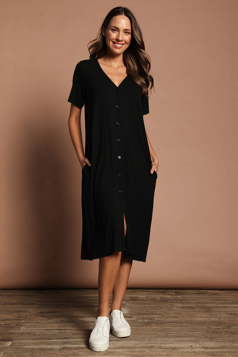 Model Madeline wearing size 10 of The Pack & Go Luxe Bamboo Button Up Dress with Pockets in colour Black (Black), from the front, showing the whole outfit