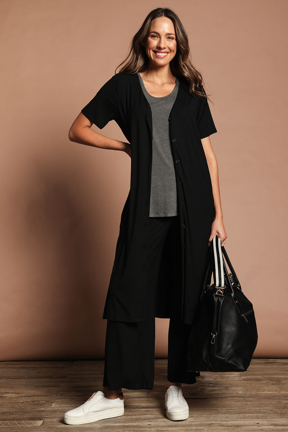 Model Madeline wearing size 10 of The Pack & Go Luxe Bamboo Button Up Dress with Pockets in colour Black (Black), from the front, showing the whole outfit