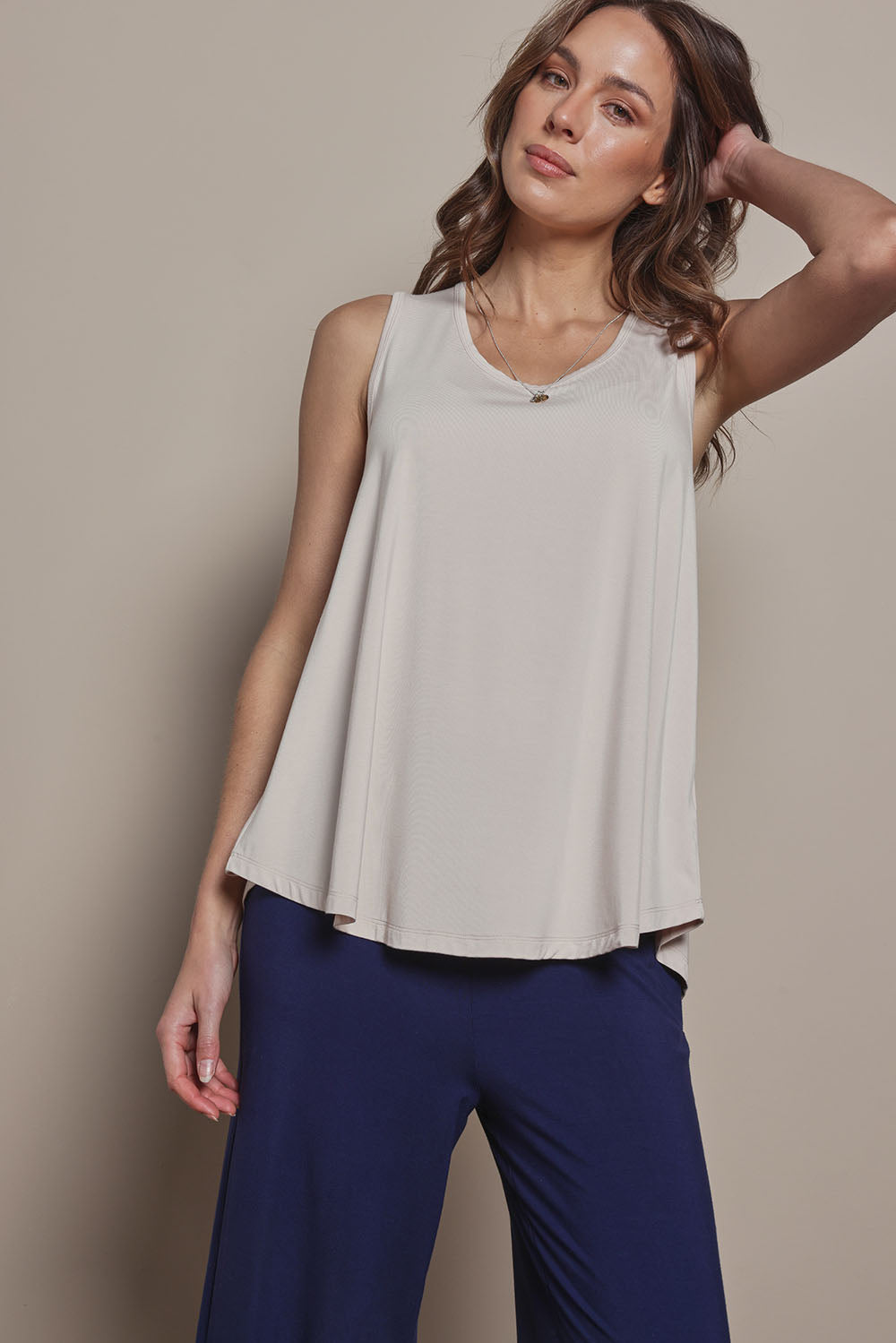 Model Madeline wearing size 10 of The Pack & Go Luxe Bamboo Swing Tank in colour Nougat, from the front, cropped image