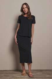 Model Madeline wearing size 10 of The Pack & Go Luxe Bamboo Pull On Maxi Skirt in colour Black (Black), from the front, showing the whole outfit