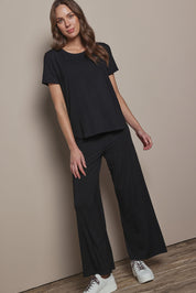 Model Madeline wearing size 10 of The Pack & Go Luxe Bamboo Tee in colour Black (Black), from the front, showing the whole outfit