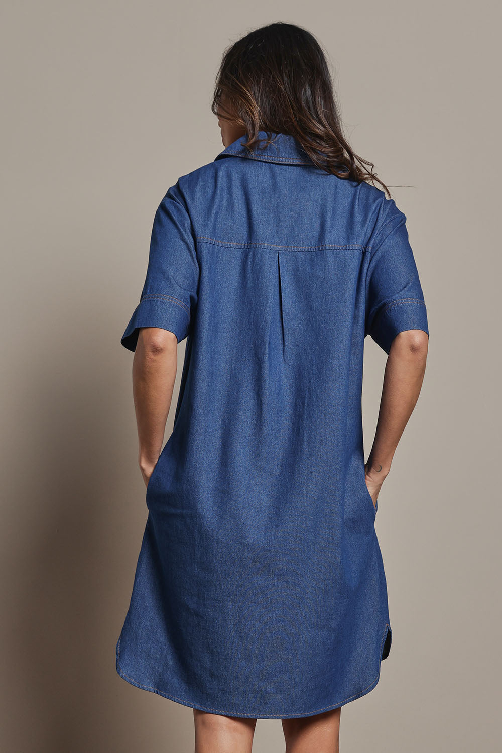 Model Amanda wearing size 10 of The S/S Chambray Shacket Dress With Pockets in colour Denim (Blue), from the back