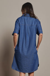 Model Amanda wearing size 10 of The S/S Chambray Shacket Dress With Pockets in colour Denim (Blue), from the back