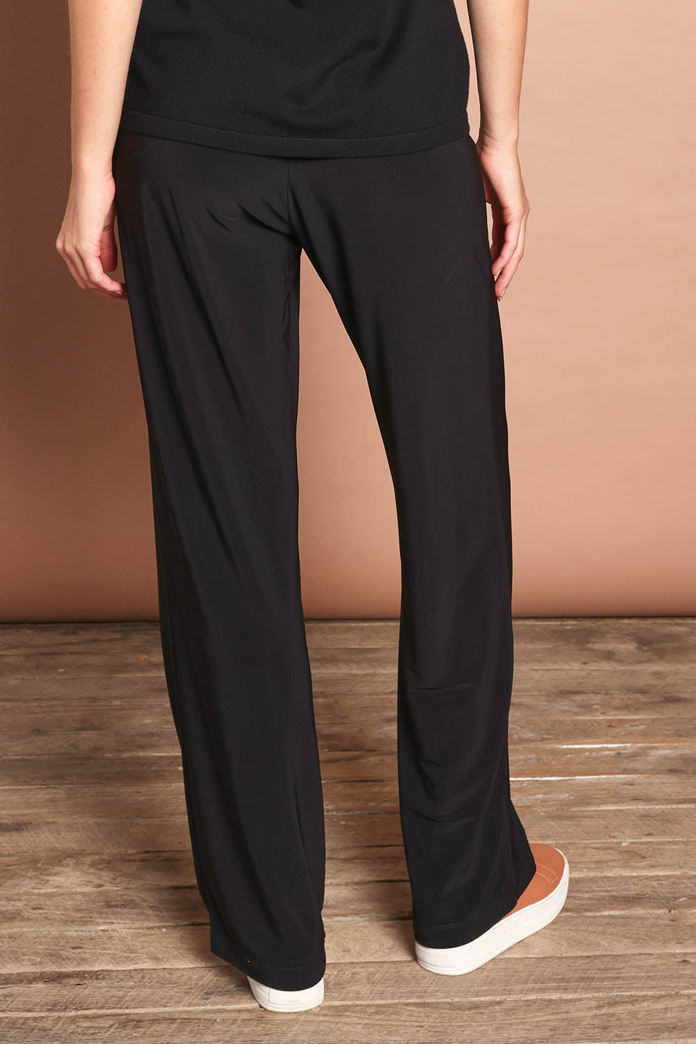 Model Madeline wearing size 10 of The Travel Wide Leg Pant in colour Black (Black), from the back