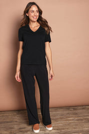 Model Madeline wearing size 10 of The Travel Wide Leg Pant in colour Black (Black), from the front, showing the whole outfit