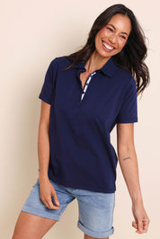Model Amandam wearing size 10 of the The Keepers Polo Tee – Navy in colour Navy, in a cropped view