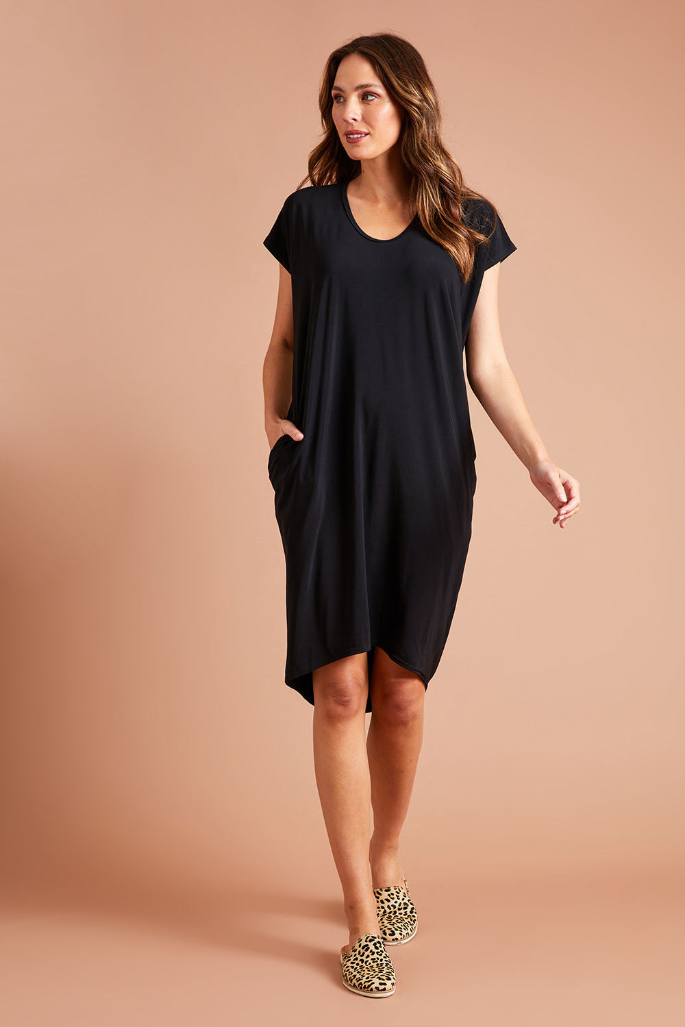 Model Madeline wearing size 10 of The Drape Jersey Dress in colour Black (Black), from the front, showing the whole outfit