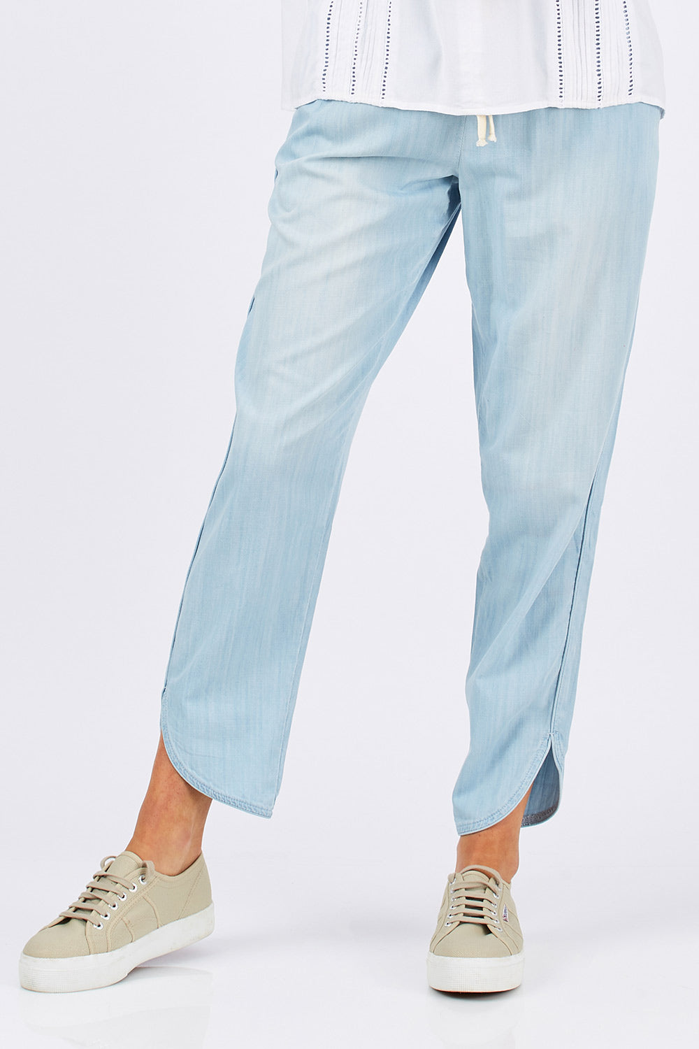 Model Clementine wearing size 10 of The Chambray Curved Hem Pant in colour Chambray (Blue), from the front, cropped image