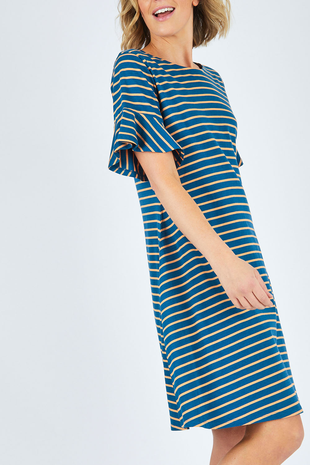 Model Chelsea wearing size 10 of The Cotton Bamboo Frill Dress in colour Bluegold (Blue), from the front, cropped image