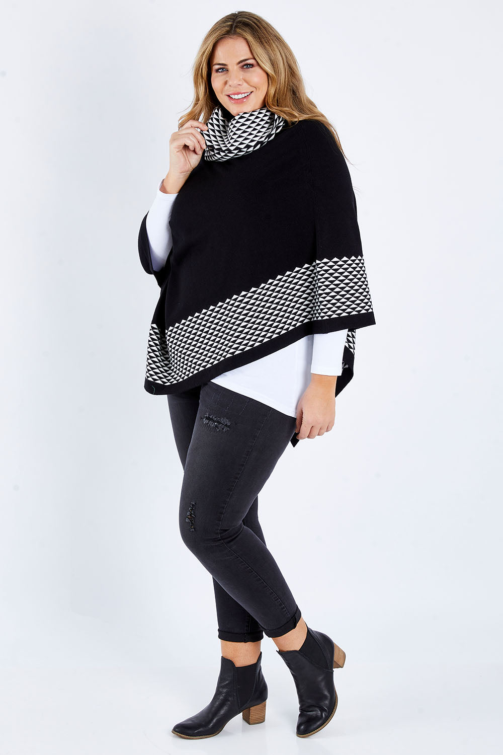 Model Fiona wearing size L-XL of The Patterned Removable Roll Neck Poncho in colour Blackprint (Black), from the front, showing the whole outfit