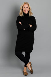 Model Sandy wearing size S of The Roll Neck Tunic Dress in colour Black (Black), from the front, showing the whole outfit