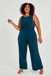 Model Alexis wearing size 18 of The Cross Waist Jumpsuit in colour Darkteal (Green), from the front, showing the whole outfit