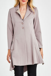 Model Kelly wearing size 10 of The Asymmetrical Hem Coat in colour String, from the front, cropped image